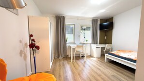 A compact room with a bed, a desk, a chair, and a radiator.