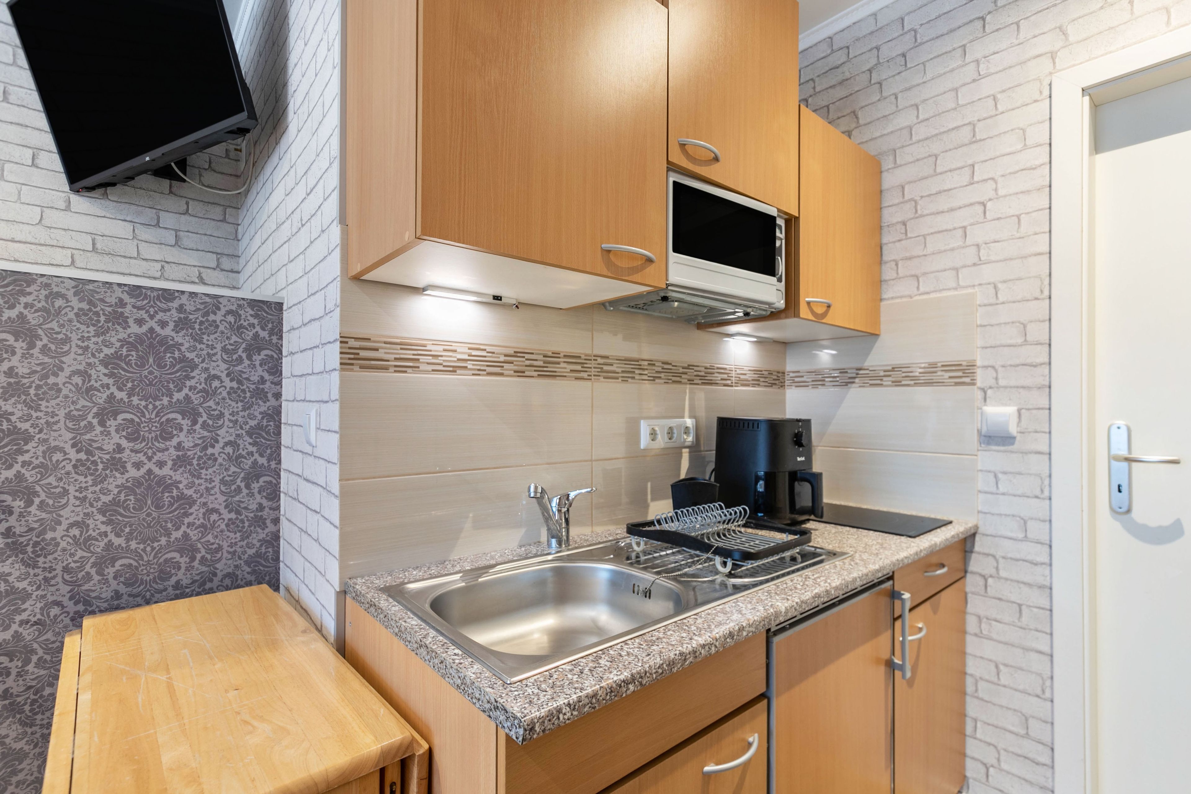 Een moderne keuken met granieten aanrechtbladen, roestvrijstalen apparatuur en houten kastjes.