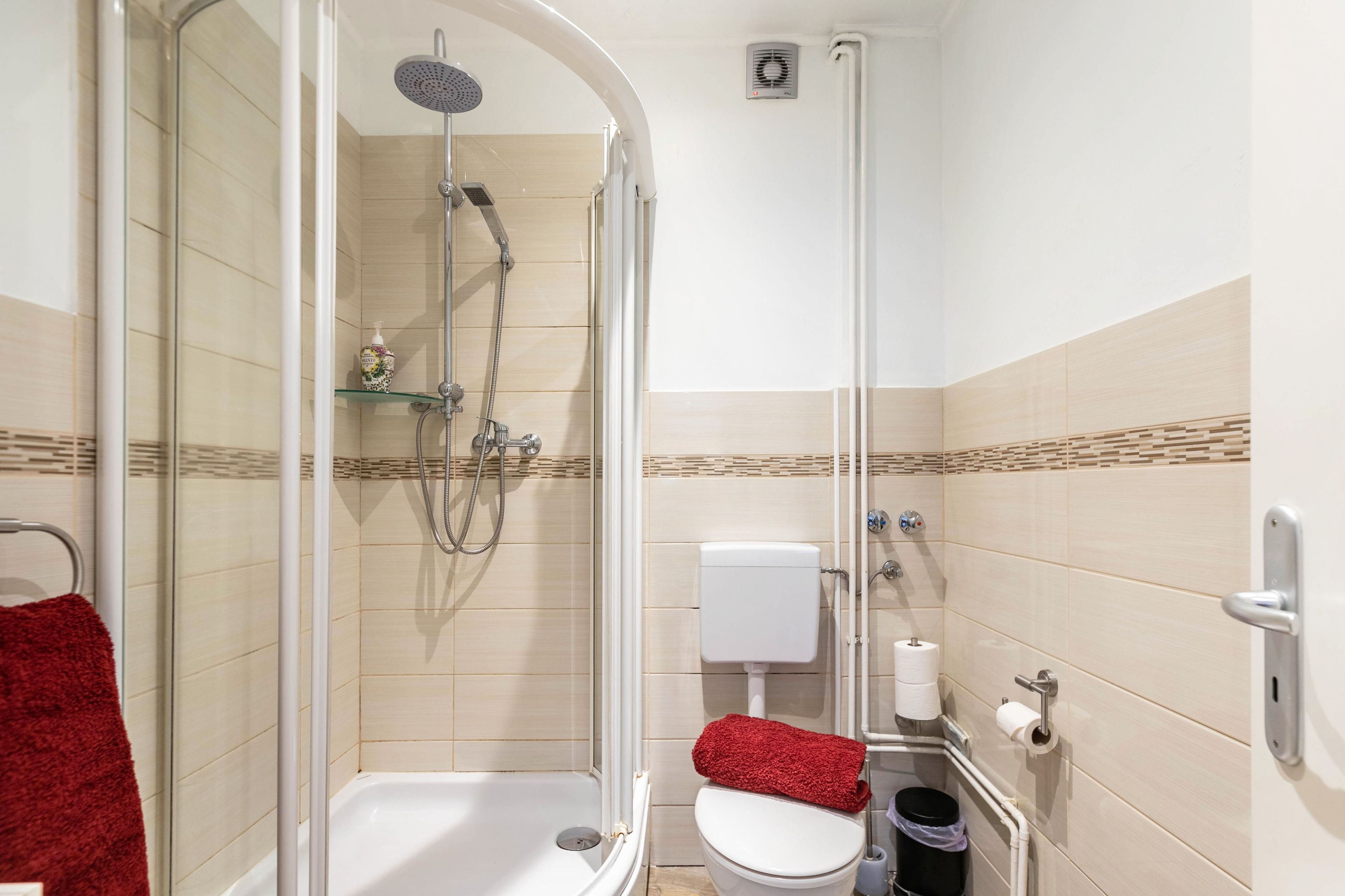 A modern bathroom with a glass-enclosed shower, a toilet, and a bidet.