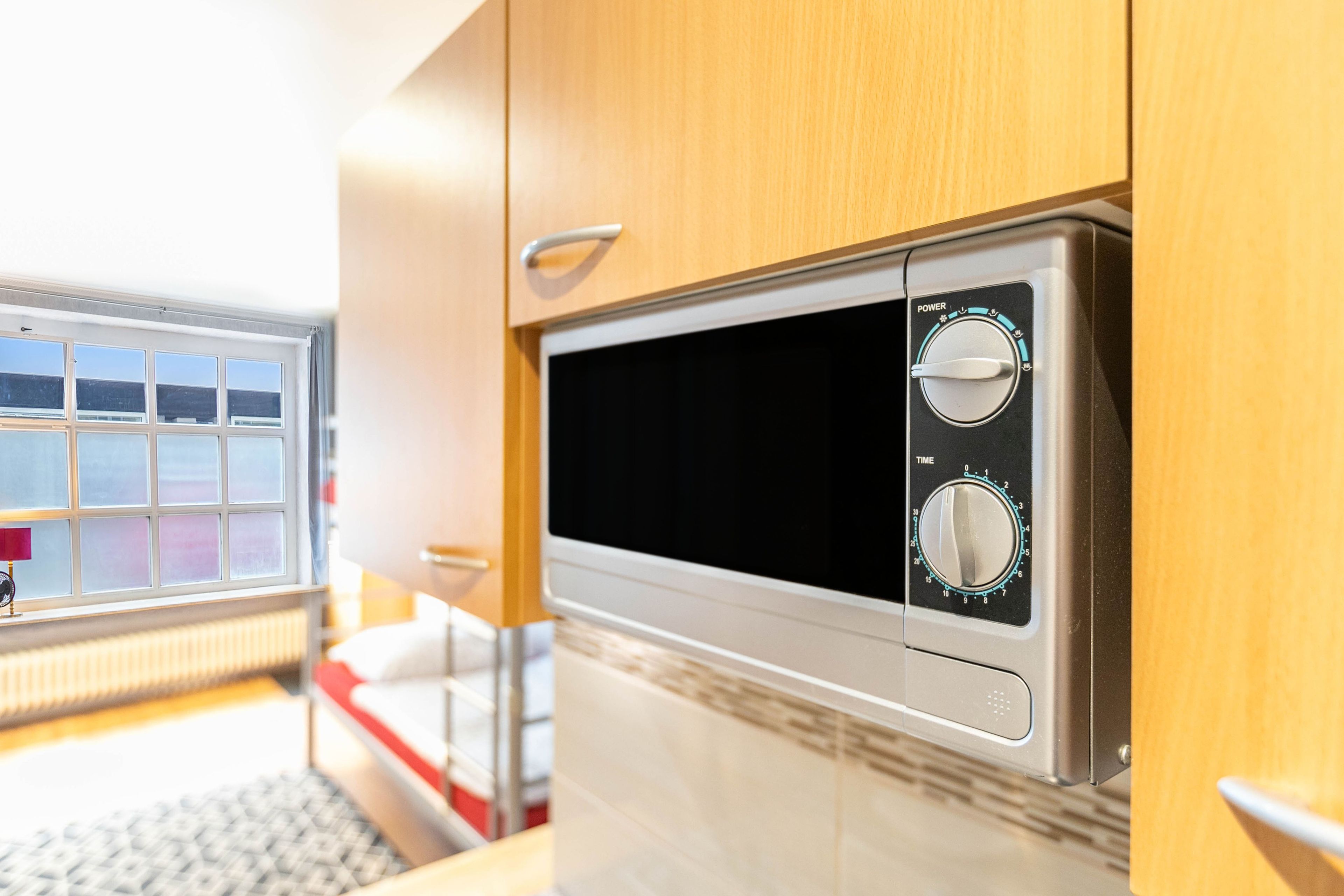 A compact kitchen with a microwave, a power dial, and a timer dial.