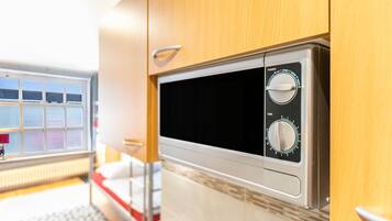 A compact kitchen with a microwave, a power dial, and a timer dial.
