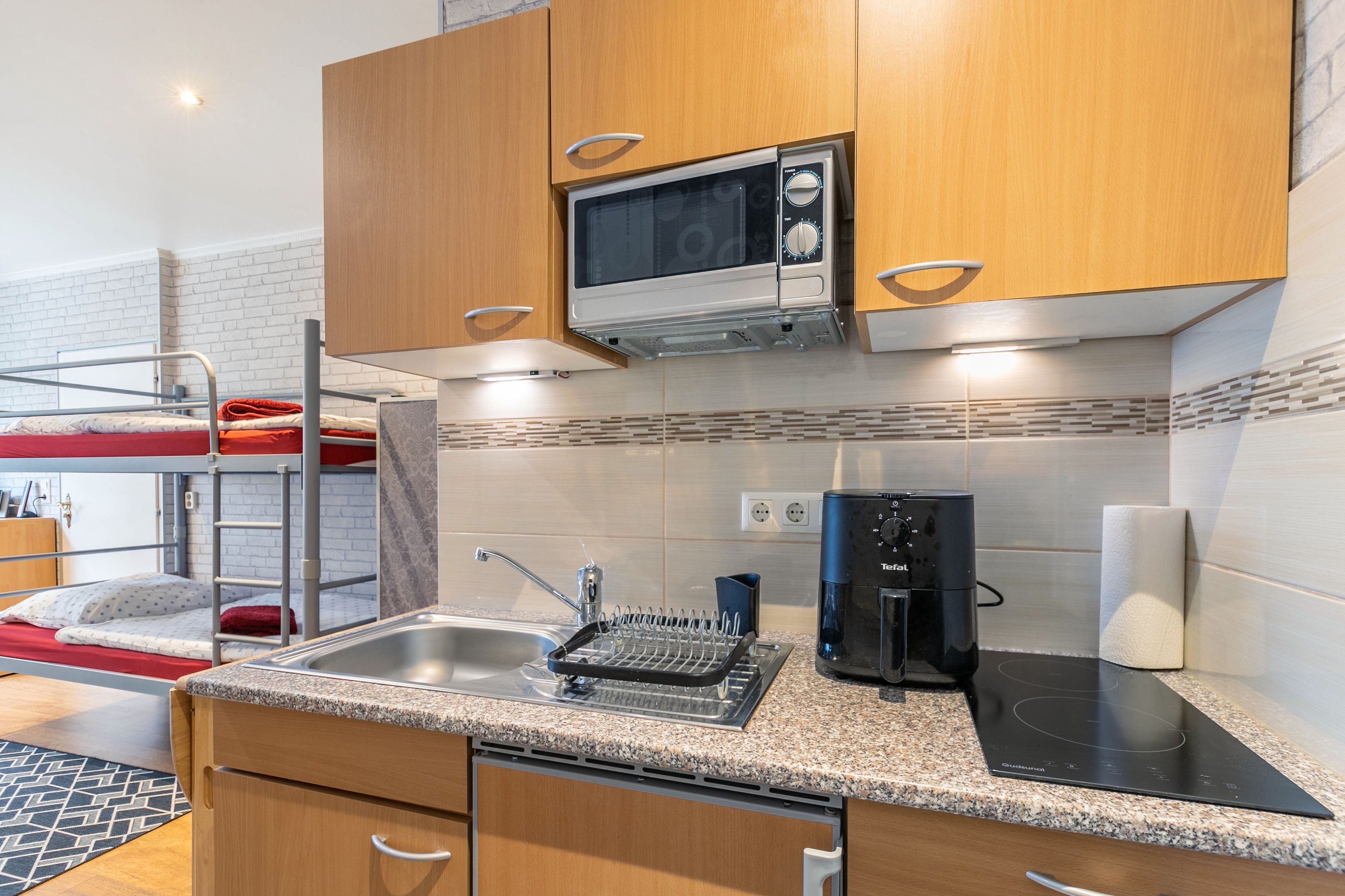 A compact kitchenette with a microwave, kettle, and induction cooktop.