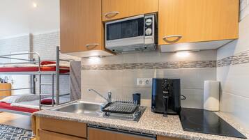 A compact kitchenette with a microwave, kettle, and induction cooktop.