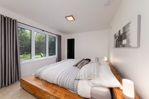 Une chambre à coucher moderne avec un grand lit, une vue sur l’extérieur et un tableau accroché au mur.