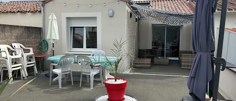 A patio area with a table and chairs, a red planter, and a covered seating area.