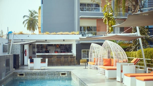 Un área de piscina en la azotea con sillones de descanso y un bar.
