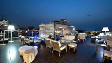 Un área de lounge en la azotea con asientos exteriores y un bar.