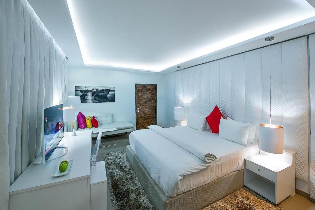 A modern hotel room with a bed, bedside tables, a desk, and a chair.