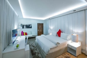 Una habitación de hotel moderna con cama, mesitas de noche, un escritorio y una silla.