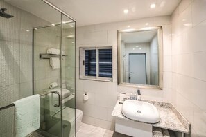 A modern bathroom with a glass shower enclosure, a marble sink, and a large mirror. - Maison Hotel By Fahrenheit  (Lagos)