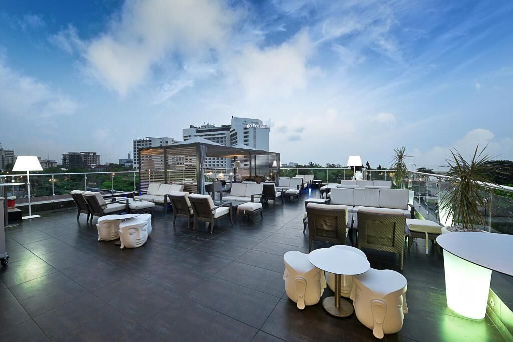 Una terraza en la azotea con mobiliario exterior, vistas del horizonte urbano y arquitectura moderna.