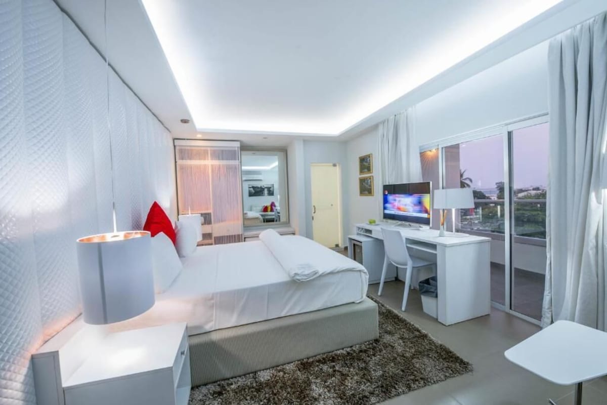 A modern hotel room with a bed, desk, and television.