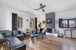 Ein modernes Wohnzimmer mit einer Couch, Sesseln, einem Kamin und einem Deckenventilator.
