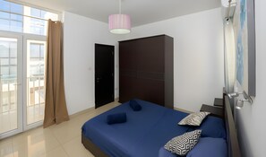 Een slaapkamer met een bed, een kledingkast, een deur en een raam.