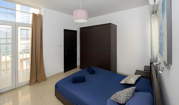 A bedroom with a bed, a wardrobe, a door, and a window.