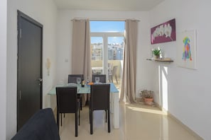 A dining area with a table, chairs, and a view of buildings through a window.