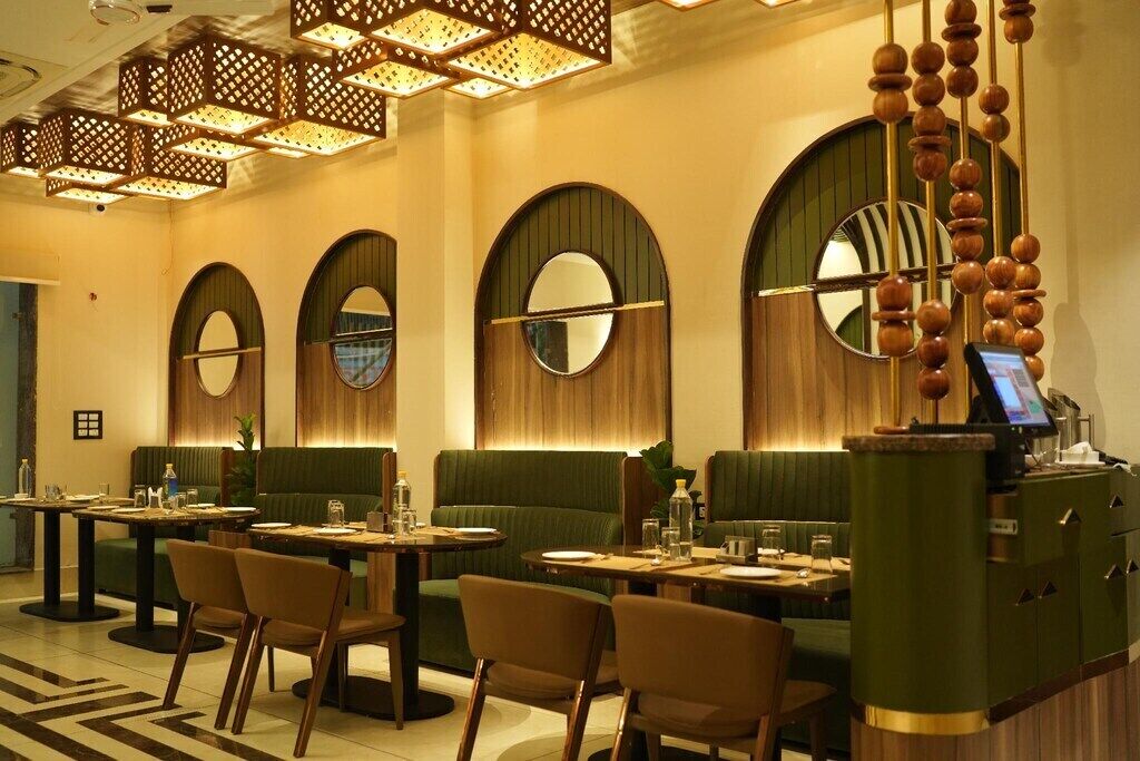 A restaurant with round tables, green booths, and a bar area.