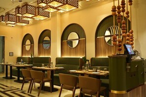 A restaurant with round tables, green booths, and a bar area.