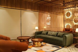 A modern living room with a green sofa, round coffee tables, and a patterned rug.