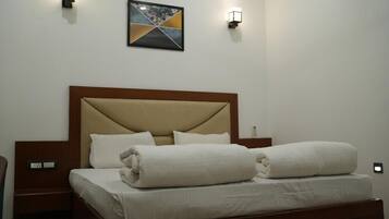 A hotel room with a bed, bedside tables, and wall-mounted lights.