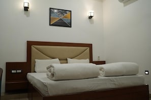 Una habitación de hotel con cama, mesitas de noche e iluminación en la pared.