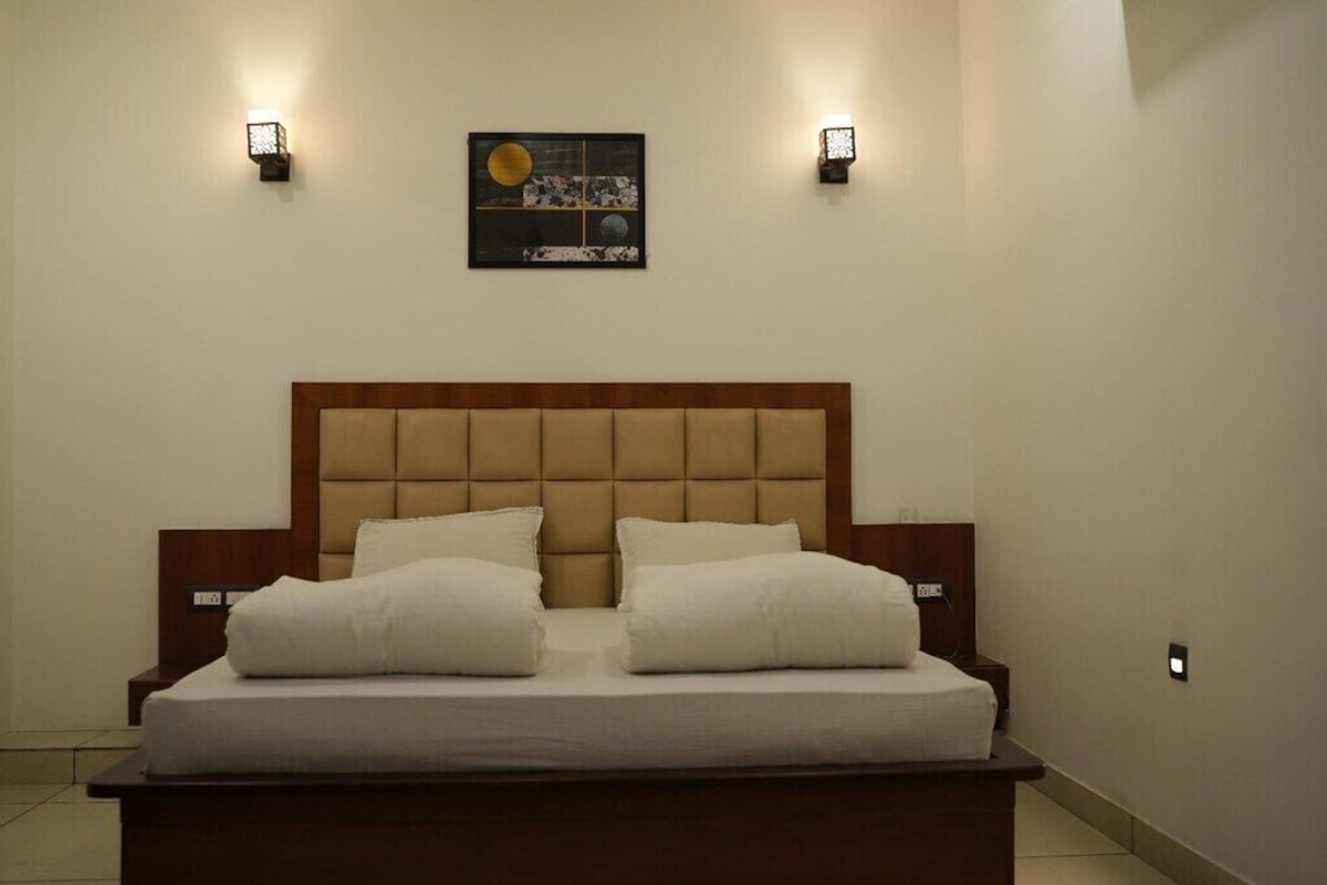Un dormitorio con una cama grande, dos mesitas de noche y luces fijadas en la pared.