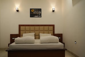 Un dormitorio con una cama grande, dos mesitas de noche y luces fijadas en la pared.