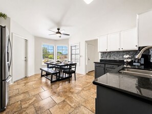 A kitchen with a dining area, a ceiling fan, and a view of the outdoors. - Peoria Home | Pool | Game Room (Peoria)