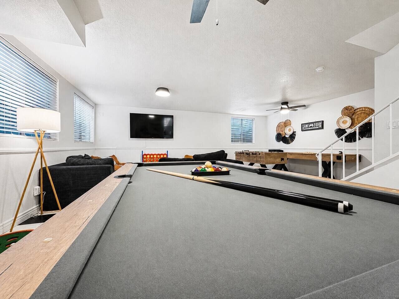 A pool table with a billiard cue, balls, and a pool table cover.
