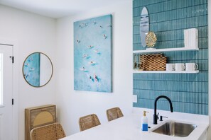 A modern kitchen with a white countertop, a sink, and a blue tiled backsplash. - The Cove Reunion HQ - Sleeps 22 - Gym - Game Room - Theater - Spa (Santa Rosa Beach)