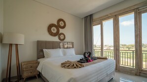 A hotel room with a large bed, a nightstand, a lamp, and a view of the outdoors. - Villa Lopina Umalas (Kuta Utara)