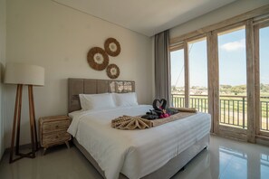 Habitación de hotel con una cama grande, una mesita de noche, una lámpara y vistas al exterior.