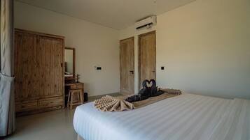 A hotel room with a large bed, wooden wardrobe, and a mirror.