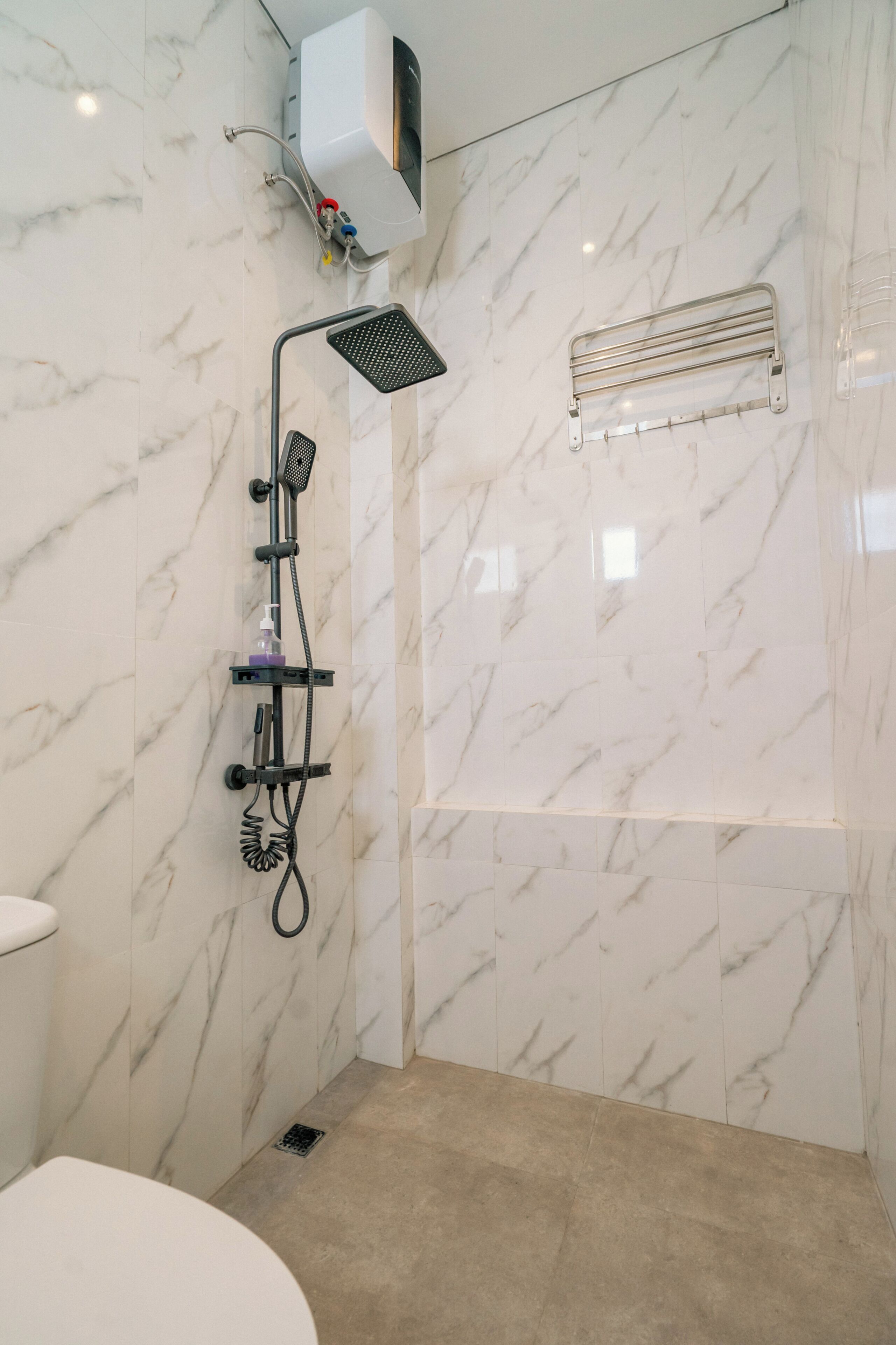 Un baño con ducha, inodoro y barra para toallas.