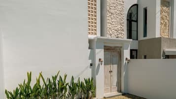 A modern house with a white exterior, a stone accent wall, and a small front yard with plants.