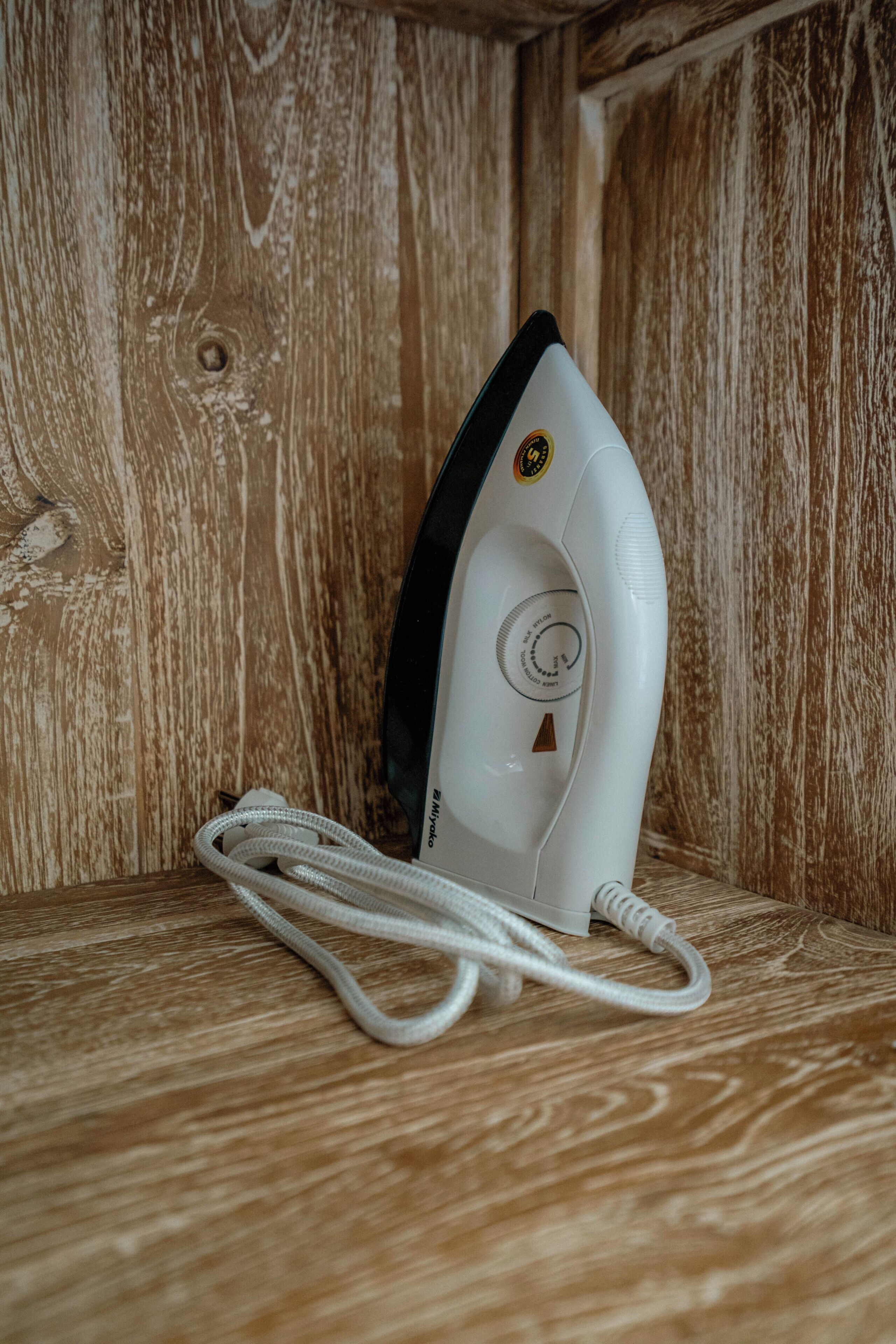 A white iron appliance with a cord, placed on a wooden surface.