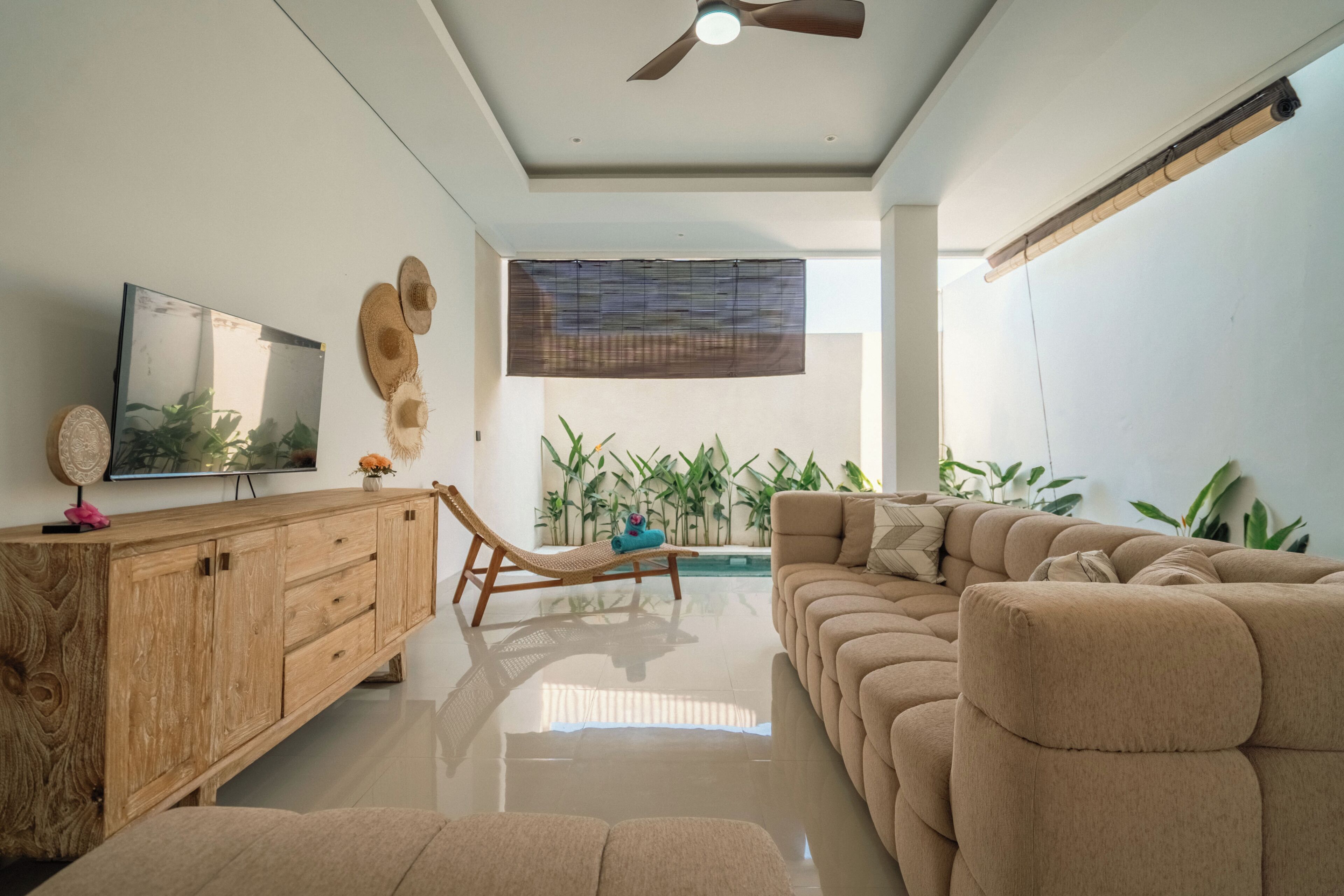 Una sala de estar moderna con un sofá, un mueble de madera, un televisor y un ventilador de techo.