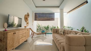 Una sala de estar moderna con un sofá, un mueble de madera, un televisor y un ventilador de techo.