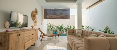A modern living room with a sofa, a wooden cabinet, a TV, and a ceiling fan.