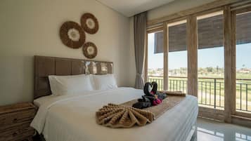 Habitación de hotel con una cama grande, cabecero de madera y vistas al exterior a través de amplios ventanales.