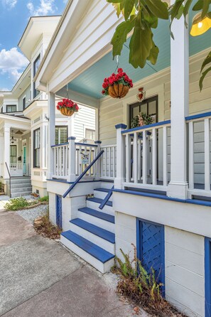 A two-story house with a front porch, a staircase with blue railings, and a mailbox. - Blue Water Cottage | Porch, Courtyard, Office by Lucky Savannah (Savannah)