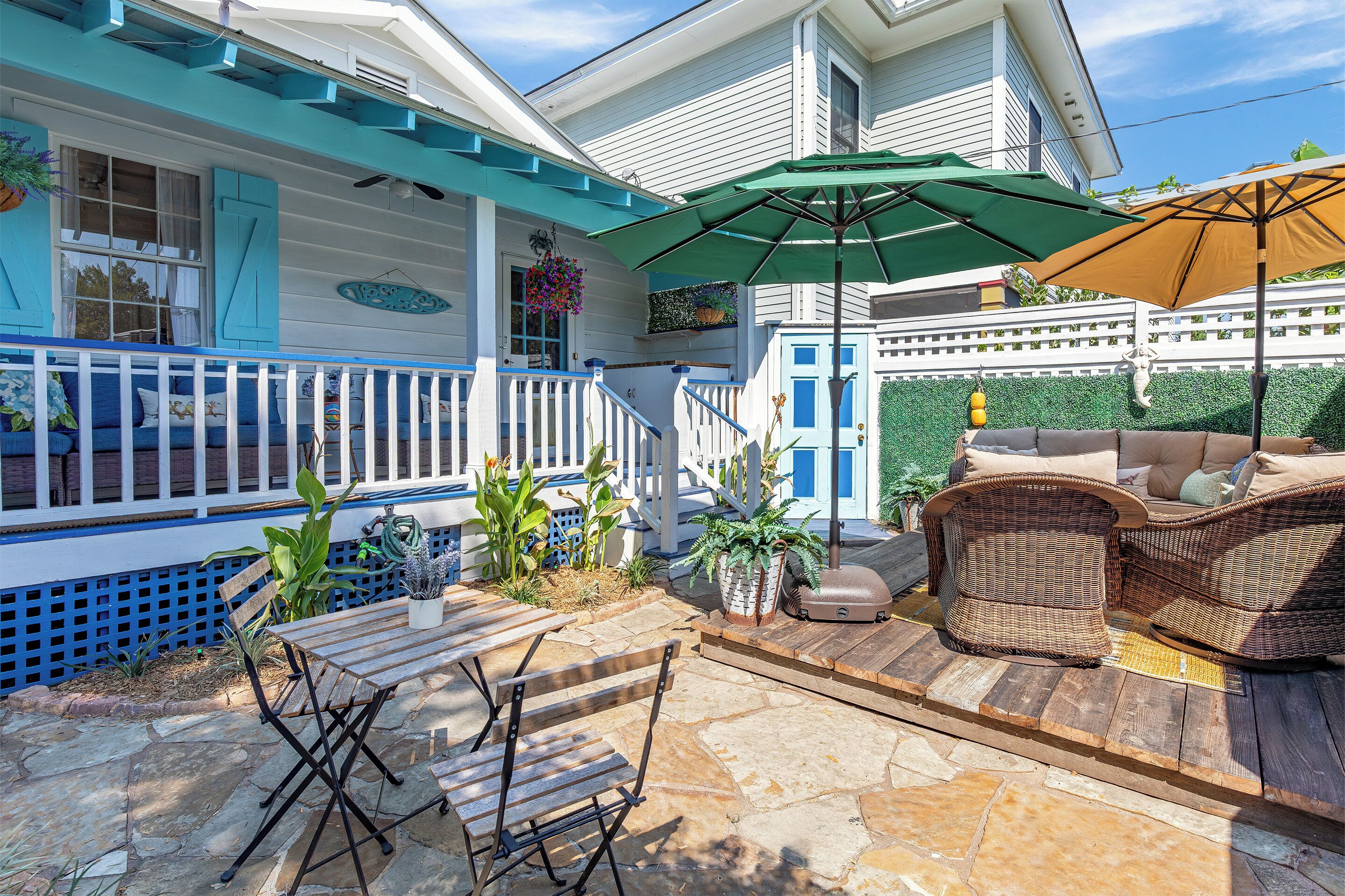 A covered patio area with outdoor furniture, a wooden table, and a wicker sofa.