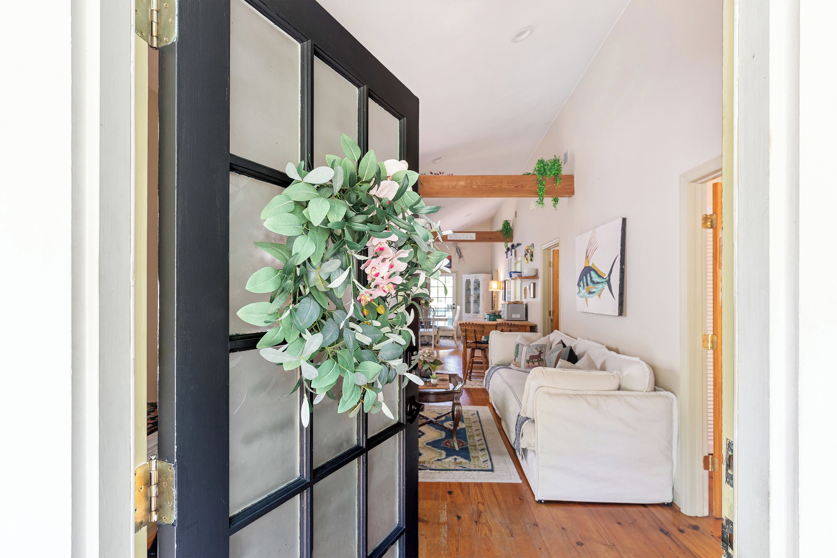 Una habitación con un sofá blanco, piso de madera y una planta colgante.