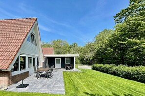 A two-story house with a patio, a dining area, and a covered outdoor kitchen. - Holiday home with 3 bedrooms (Oostkapelle)