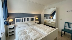 Una camera da letto con un letto, comodini, uno specchio e una sedia.