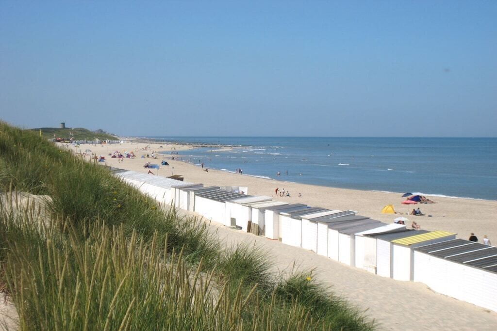 A beach with white buildings, a sandy shore, and the ocean.