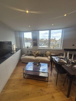 A modern living space with a sofa, dining table, and kitchen area. - Elegant Sloane Gate Residence | 2 Bed - 2 Bath (Greater London)