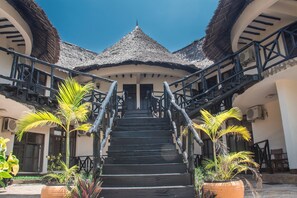 A staircase leading to a building with a thatched roof and a balcony. - Millennium Sea Breeze Resort (Pwani Bagamoyo)