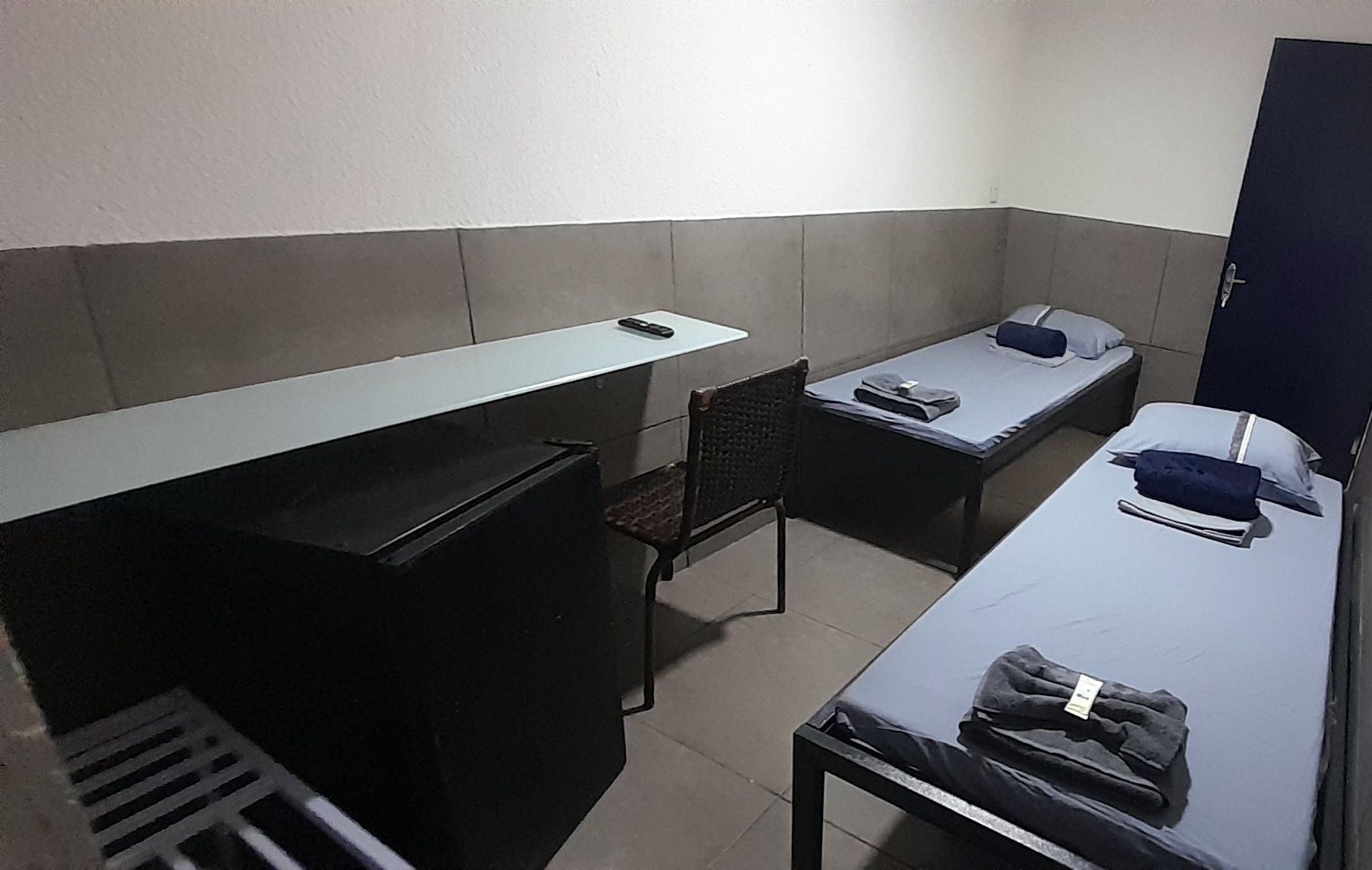 Una habitación tipo dormitorio con escritorio, dos camas individuales, una silla y un armario.