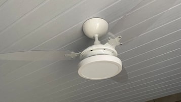 Un ventilador de techo en una habitación con piso de baldosas y un espejo colgado en la pared.